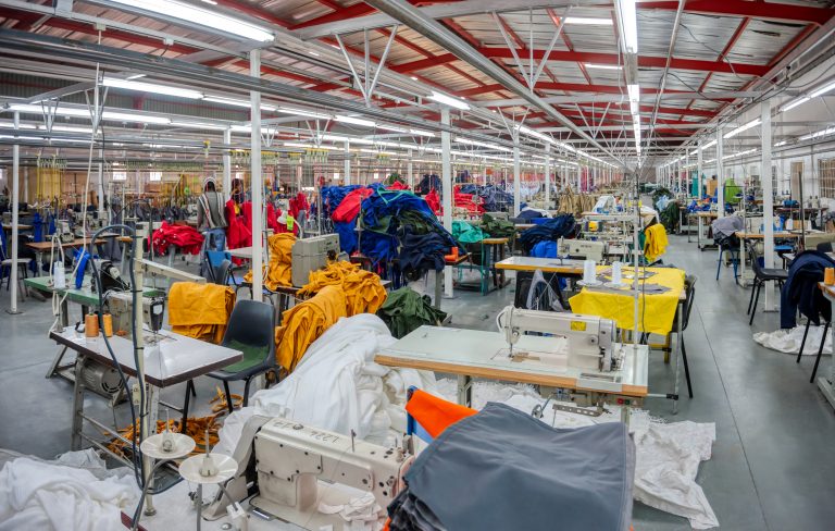 Fábrica têxtil, máquinas e tecidos coloridos em cima das mesas