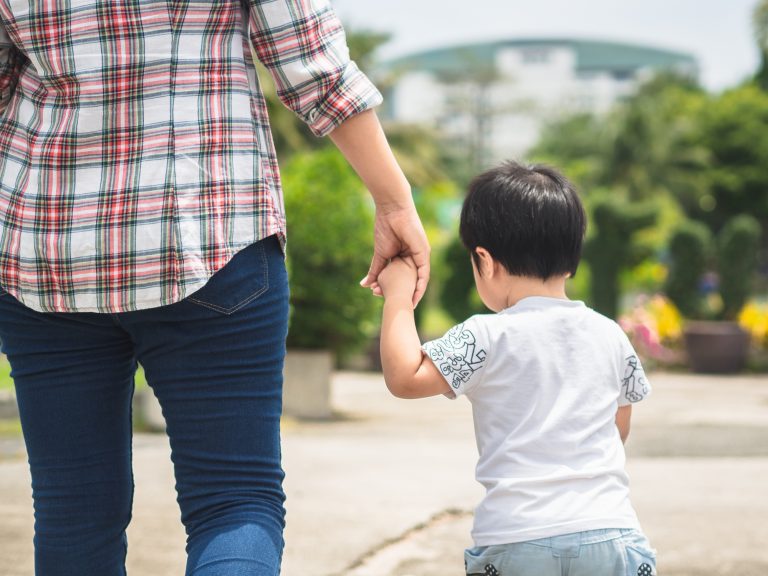 Mulher e criança de mãos dadas caminhando