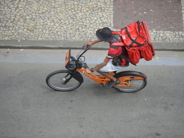 Trabalhador de entrega por aplicativo percorre ruas de bicicleta no centro do Rio de Janeiro