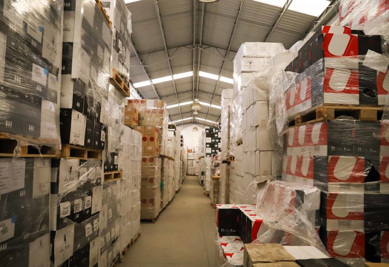 Galpão de armazenamento com muitas caixas empilhadas, embaladas para envio