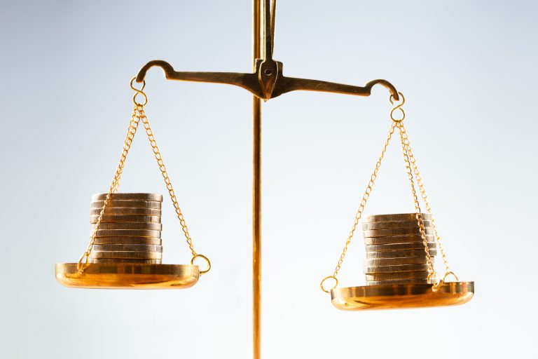 Balança de dois pratos com pilhas de moedas equilibrando os lados