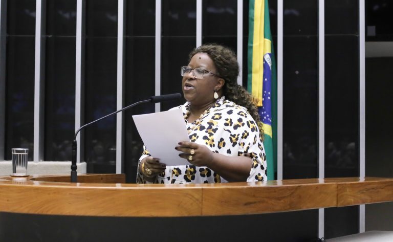 Ministra Direitos Humanos, Macaé Evaristo. Ela é uma mulher negra, usa óculos e uma blusa branca com estampas