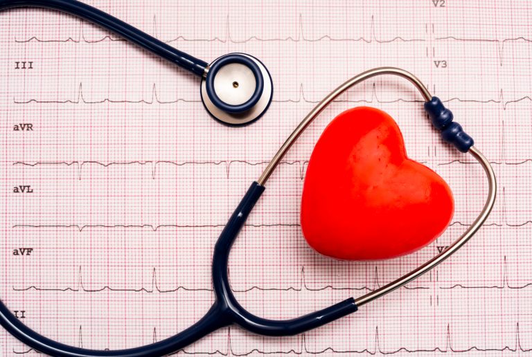 Imagem mostra estetoscópio e bolinha de massagem em formato de coração em cima de um eletrocardiograma
