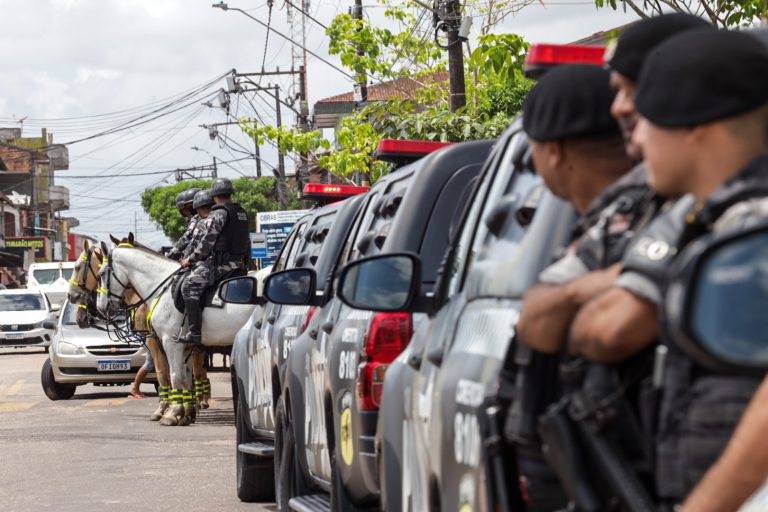 Policiais ao lado de viaturas